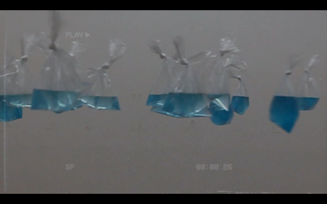 bags of blue water hang in front of a white wall so that they form a horizon line.